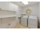 Well-lit laundry room with ample storage, including white shelving and upper cabinets at 9349 E Calle De Valle Dr, Scottsdale, AZ 85255