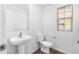 Half bathroom features a pedestal sink, toilet, and a window with blinds at 935 E Agua Fria Ln, Avondale, AZ 85323