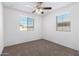 Cozy bedroom with a ceiling fan, carpeted floor, and natural light from two windows at 935 E Agua Fria Ln, Avondale, AZ 85323