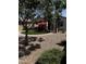 Well-kept backyard with gravel landscaping, artificial grass, red umbrella seating, and a covered patio at 10704 E Twister Ave, Mesa, AZ 85212