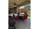 Covered patio features a ceiling fan, red cushioned seating with a red umbrella, and a gas grill at 10704 E Twister Ave, Mesa, AZ 85212