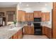 Kitchen with granite countertops, wood cabinets, and modern black appliances at 11242 E Onza Ave, Mesa, AZ 85212