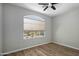 Bright bedroom features neutral walls, laminate flooring, a ceiling fan, and large window with a shade at 1398 W Windhaven Ave, Gilbert, AZ 85233