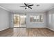 Bright living room with hardwood floors, white trim, shutters, ceiling fan and sliding door to the outdoor patio at 1398 W Windhaven Ave, Gilbert, AZ 85233