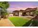 Expansive backyard with lush artificial grass, a covered patio, and desert landscaping at 15456 W Corrine Dr, Surprise, AZ 85379