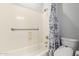 Standard white bathtub shower combination with gray tile accents and gray shower curtain at 15456 W Corrine Dr, Surprise, AZ 85379