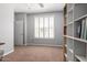 Bright, neutral-toned office with a window, closet, and modern shelves providing ample storage and natural light at 15456 W Corrine Dr, Surprise, AZ 85379