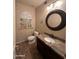 Half bath featuring vanity with granite counter, a round mirror and unique wall art at 2301 E Beachcomber Dr, Gilbert, AZ 85234