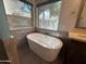 Freestanding tub beside a textured brick accent wall creates a calming atmosphere for relaxation at 2301 E Beachcomber Dr, Gilbert, AZ 85234