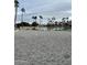 Sandy beach volleyball court near the pool with palm trees under a cloudy sky at 2301 E Beachcomber Dr, Gilbert, AZ 85234