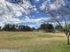 Wide open field with goal posts and mature trees under a beautiful blue sky with clouds at 2301 E Beachcomber Dr, Gilbert, AZ 85234