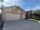 Charming single-story home with a three-car garage, lush lawn, and a beautifully landscaped yard with a palm tree at 2301 E Beachcomber Dr, Gilbert, AZ 85234