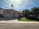 Charming single-story home with a three-car garage, lush lawn, and a beautifully landscaped yard with a palm tree at 2301 E Beachcomber Dr, Gilbert, AZ 85234