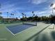 Well-maintained tennis court with blue and green surface, surrounded by palm trees and lush landscaping at 2301 E Beachcomber Dr, Gilbert, AZ 85234