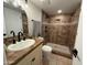Bathroom with walk-in shower featuring tiled surround and dark fixtures, plus granite countertop and basin sink at 2331 W Via Rialto Cir, Mesa, AZ 85202