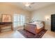 Light-filled bedroom features a ceiling fan, shuttered windows, vintage desk, and tile flooring at 2413 E Rancho Dr, Phoenix, AZ 85016