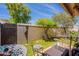 Private patio area with lush green grass, mature trees, decorative metal art, and outdoor seating at 2413 E Rancho Dr, Phoenix, AZ 85016