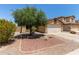 Single-story home with a two-car garage, mature shade tree, and desert landscaping for low maintenance at 25060 W Vista Norte St, Buckeye, AZ 85326