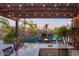 Inviting outdoor kitchen featuring a granite countertop, stone accents, and a pergola with string lights, overlooking the pool at 26285 N 89Th St, Scottsdale, AZ 85255