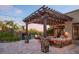Stunning outdoor kitchen and patio area with granite countertops, a pergola with string lights, and views of the custom pool at 26285 N 89Th St, Scottsdale, AZ 85255