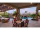 Elegant outdoor dining and kitchen area with a stone-clad kitchen, pergola, and views of the luxurious pool and water features at 26285 N 89Th St, Scottsdale, AZ 85255