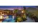 Beautiful backyard oasis featuring a luxurious pool, rock waterfalls, fire bowls and desert landscaping at dusk at 26285 N 89Th St, Scottsdale, AZ 85255