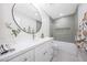 Modern bathroom featuring a large round mirror, white vanity, brushed gold hardware and gray tile tub surround at 4079 E Yucca St, Phoenix, AZ 85028