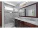 Bathroom featuring dual sinks, a walk-in shower, a large mirror and wood cabinetry at 4239 E Azalea Dr, Gilbert, AZ 85298