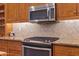 Close-up of the kitchen range, microwave, tile backsplash, granite countertop and custom wood cabinetry at 4239 E Azalea Dr, Gilbert, AZ 85298