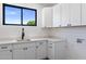 Efficient laundry room featuring white cabinets and quartz countertop with a black faucet at 4301 E Sells Dr, Phoenix, AZ 85018