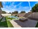 Spacious backyard featuring a pool, fire pit, artificial grass, and privacy wall at 4667 E Reins Rd, Gilbert, AZ 85297