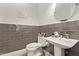 Chic powder room with stylish gray tiling, sleek fixtures, a pedestal sink, and modern decor at 4667 E Reins Rd, Gilbert, AZ 85297