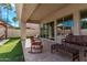 Covered patio with comfortable seating overlooks the lush backyard and sparkling pool at 4667 E Reins Rd, Gilbert, AZ 85297