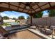 Covered patio with comfortable seating overlooks the sparkling pool and landscaped backyard at 4667 E Reins Rd, Gilbert, AZ 85297