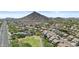An aerial view showcasing a peaceful neighborhood near scenic mountains, complete with green spaces and solar panels at 5303 W Hackamore Dr, Phoenix, AZ 85083
