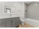 Bathroom featuring gray vanity, toilet, and a shower/tub with gray tiles at 5808 W Myrtle Ave, Glendale, AZ 85301