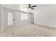 Spacious carpeted bedroom with a ceiling fan, white walls, and a glass paneled door at 5808 W Myrtle Ave, Glendale, AZ 85301