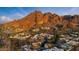 Expansive aerial view of a desert community nestled at the base of a rugged mountain range, bathed in golden light at 5905 N Echo Canyon Ln, Phoenix, AZ 85018