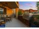 Outdoor kitchen with stainless steel grill, dining area, and beautiful mountain views at sunset at 5905 N Echo Canyon Ln, Phoenix, AZ 85018