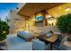 Inviting outdoor living area with comfortable seating, dining table, outdoor television, and warm lighting at 5905 N Echo Canyon Ln, Phoenix, AZ 85018