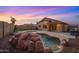 An appealing backyard features a freeform pool with rock detail, lush turf, outdoor kitchen, and desert landscaping at 6309 W Hughes Dr, Phoenix, AZ 85043