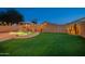 Large backyard with an artificial lawn and pool featuring a rock waterfall and lush desert landscaping at 6309 W Hughes Dr, Phoenix, AZ 85043