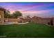 A delightful backyard boasts a freeform pool with a rock waterfall, lush turf, and privacy block fence for outdoor enjoyment at 6309 W Hughes Dr, Phoenix, AZ 85043