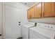 Bright laundry room with wooden cabinets, white washer, and white dryer at 6309 W Hughes Dr, Phoenix, AZ 85043