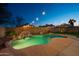 An exquisite backyard pool with a rock waterfall, set amidst lush greenery and illuminated by charming string lights at 6309 W Hughes Dr, Phoenix, AZ 85043