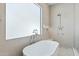 Bright bathroom featuring a soaking tub with chrome fixtures under a large window and a glass-enclosed shower at 7001 E Joan De Arc Ave, Scottsdale, AZ 85254
