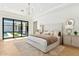 Bright primary bedroom with a plush bed, chandelier lighting, and backyard views from large glass doors at 7001 E Joan De Arc Ave, Scottsdale, AZ 85254
