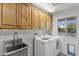 Well-lit laundry room with modern washer, dryer, utility sink, and pool view at 10024 N 61St Pl, Paradise Valley, AZ 85253