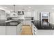 Well-lit, open kitchen with hardwood flooring, black countertops, white shaker cabinets and stainless appliances at 1018 W State Ave, Phoenix, AZ 85012