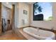 Luxurious bathroom featuring a soaking tub, glass block window, and travertine tile at 10664 E Monument Dr, Scottsdale, AZ 85262